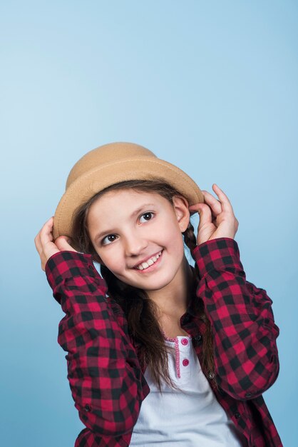 Cute girl holding hat on head 