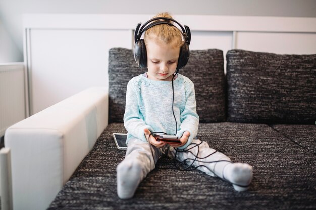 Cute girl listening to music on sofa