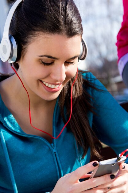 Симпатичная девушка слушает музыку со смартфоном после тренировки