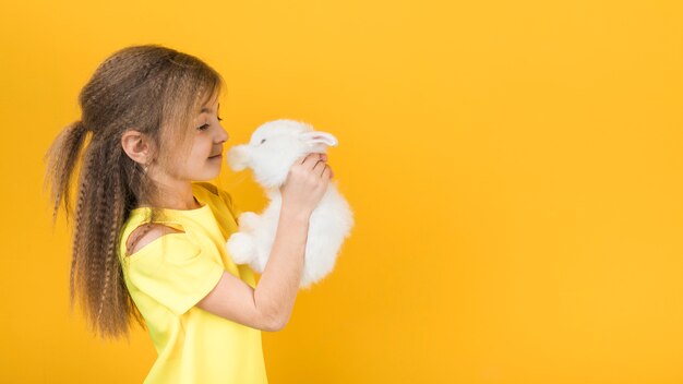 Cute girl looking at white rabbit