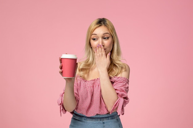 Ragazza carina ragazza adorabile con rossetto rosso in camicetta rosa che copre la bocca con una tazza rosa