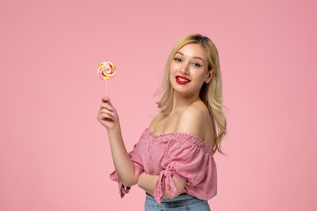 Free photo cute girl lovely young lady with red lipstick in pink blouse holding a candy sweet lollipop