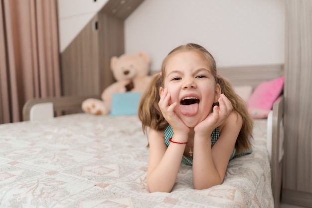 Cute girl makes funny faces on the bed