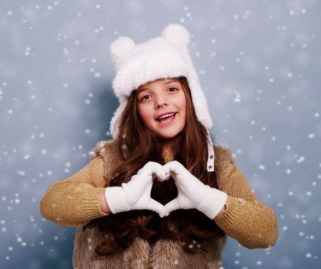 Ragazza carina che fa forma di cuore con le mani