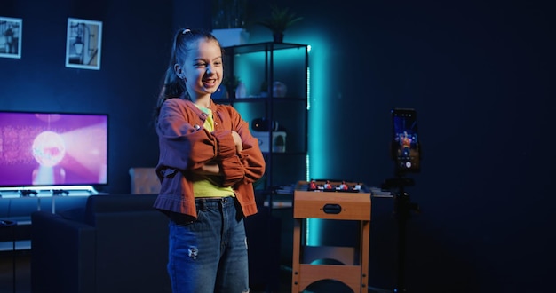 Free photo cute girl in neon lit apartment filming dance tutorial for other children watching her