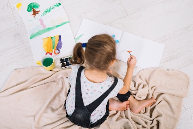 Cute girl painting with aquarelle on floor