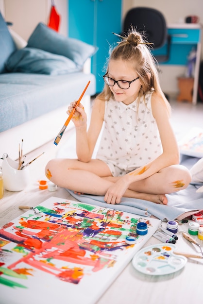 Free photo cute girl painting with gouache on floor