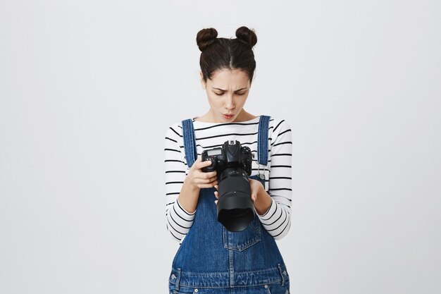 Cute girl photographer looking at camera screen, searching for perfect picture