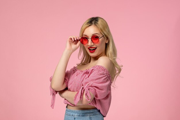 Cute girl pretty blonde lady wearing red glasses in pink shirt posing like a model and smiling