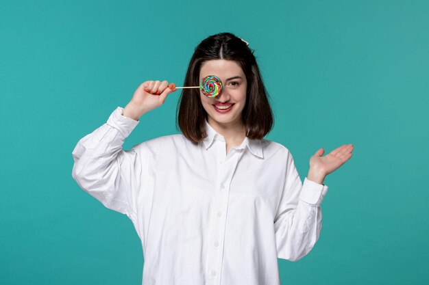 Cute girl pretty brunette young sweet girl in white shirt covering face with candy