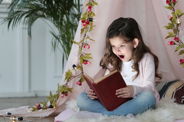 Cute girl reading a book around cute decoration