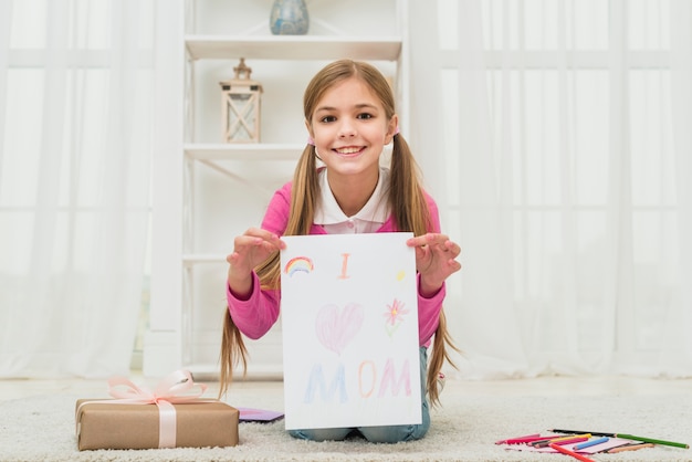 Cute girl showing drawing with I love mom inscription 