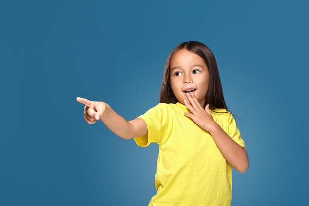 Cute girl shows her finger on blue background