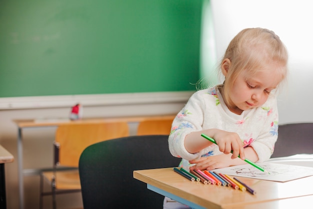 Free photo cute girl sitting and drawing