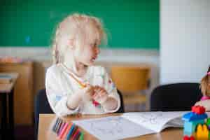 Free photo cute girl sitting at table in classroom