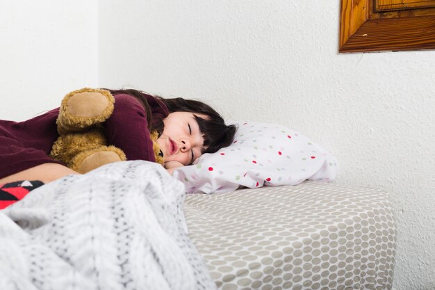 Cute girl sleeping on bed in bedroom