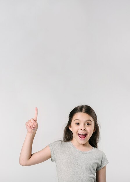 Cute girl smiling with finger up in studio