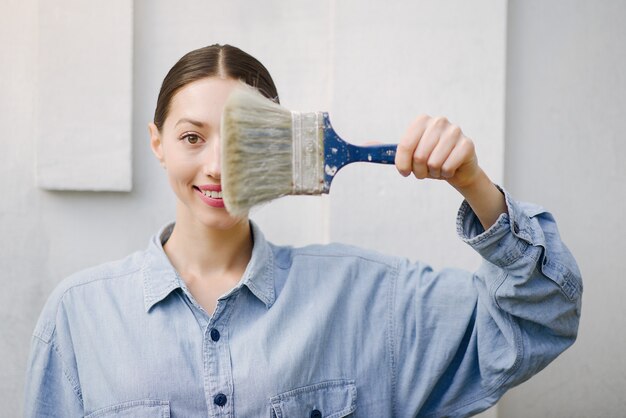 Cute girl standing near wall with repair tools