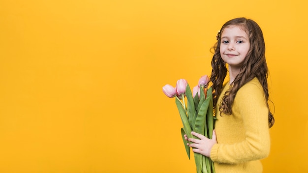 Ragazza carina in piedi con i tulipani rosa