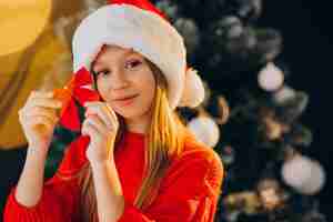 Foto gratuita adolescente sveglio della ragazza in cappello rosso della santa da albero di natale