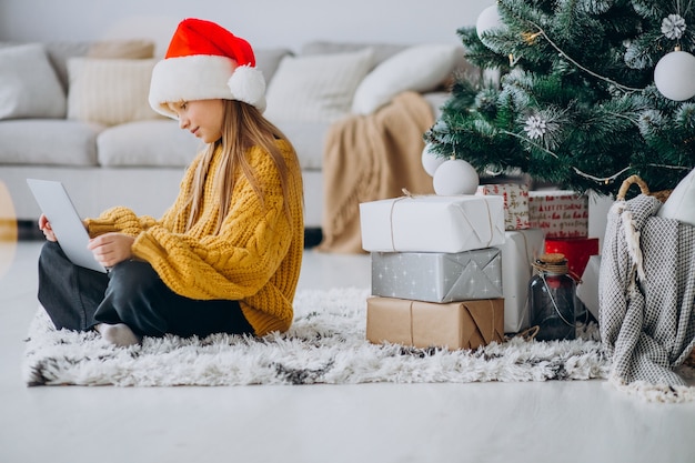 Cute girl using computer by christmas tree