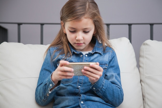 Free photo cute girl using smartphone on couch