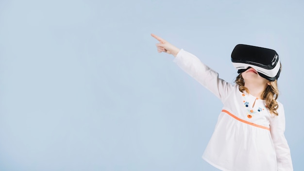 Cute girl using virtual headset pointing her finger at something