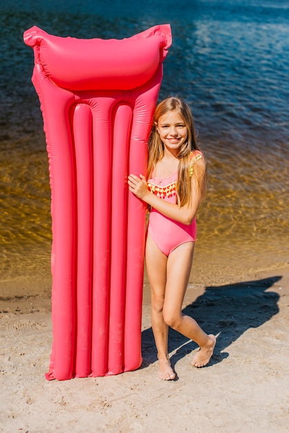 Cute girl with color air mat on seashore