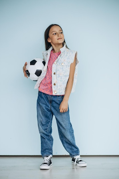 Cute girl with football ball at studio