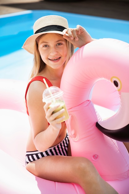 Free photo cute girl with hat holding a smoothie