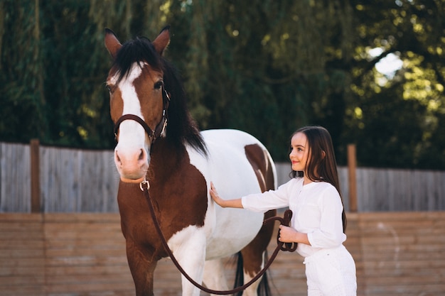 Симпатичная девушка с лошадью на ранчо
