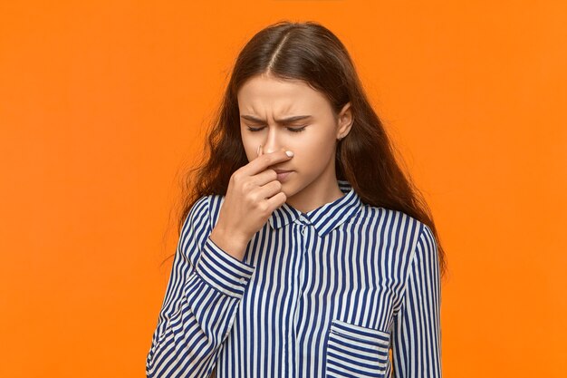 Cute girl with loose hair closing eyes, as if sneezing.