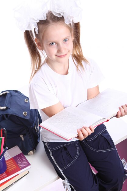 Cute girl with schoolbag sitting on the desk