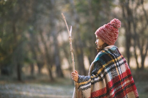 Cute girl with stick walking in forest