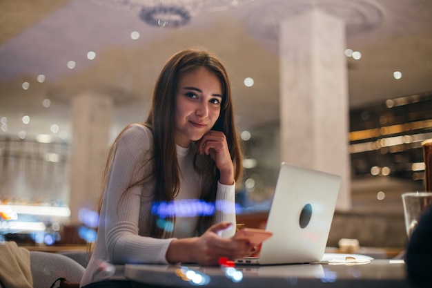 Free photo cute girl works on laptop in hipster cafe