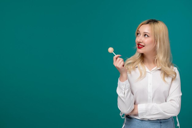 Cute girl young adorable pretty girl in a white neat shirt looking to the side with yellow candy