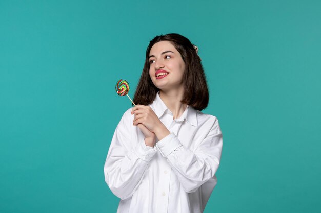 Cute girl young pretty adorable brunette girl in white shirt flirting and smiling with lollipop