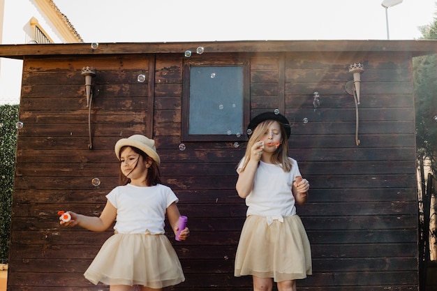 Cute girls blowing bubbles near shed