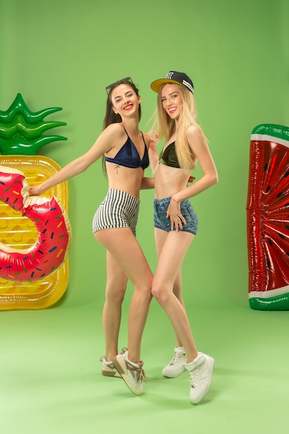 Cute girls in swimsuit posing at studio with inflatable swimming circle