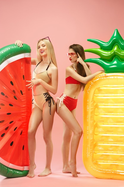 Cute girls in swimsuits posing at studio. Summer portrait caucasian teenagers