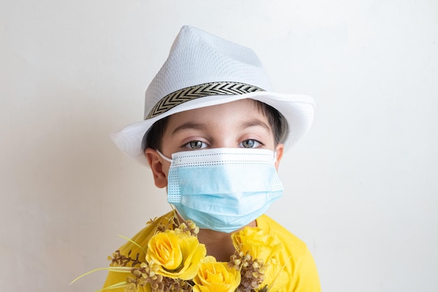 Ragazzo carino e felice con maglietta gialla con cappello bianco in testa con maschera chirurgica