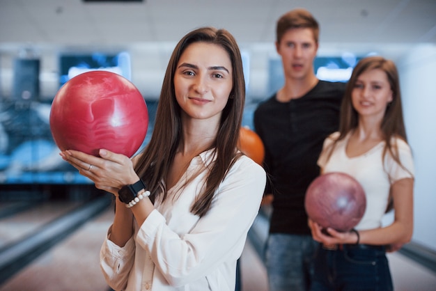 Cute happy girl. Young cheerful friends have fun in bowling club at their weekends