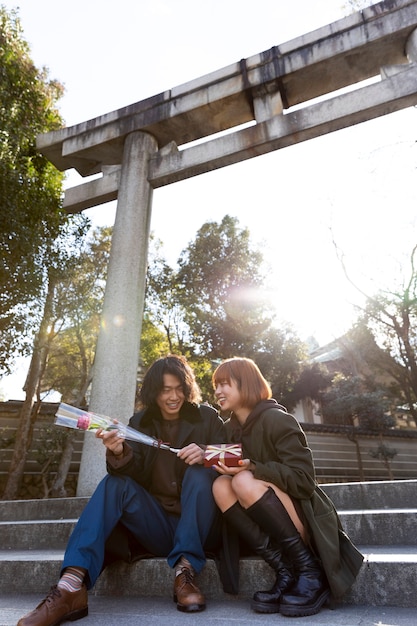 Free photo cute japanese couple exchanging white day gift outdoors