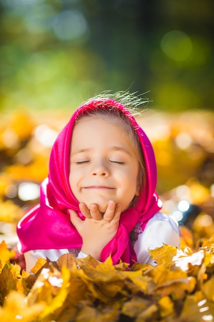 Cute kid girl in a pink shawl and dress, a white jacket like Masha and the bear from the cartoon.