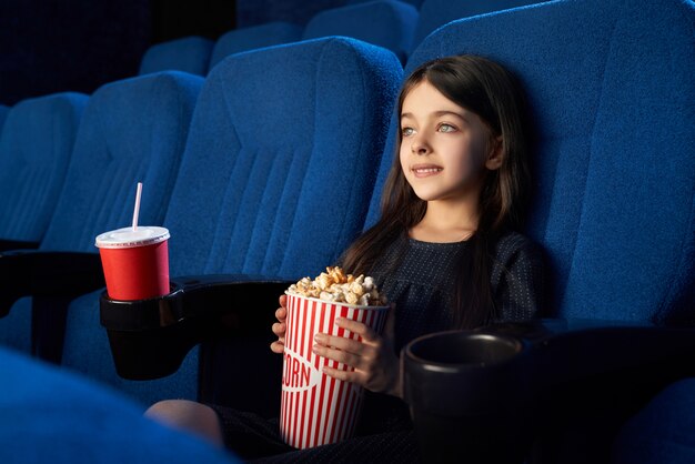 영화관에서 팝콘 양동이 함께 앉아 귀여운 꼬마.