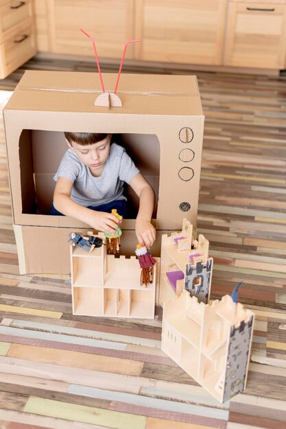 Cute kid with cardboard tv high angle