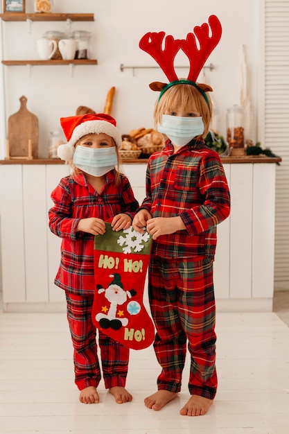 Cute kids with medical mask holding a christmas sock