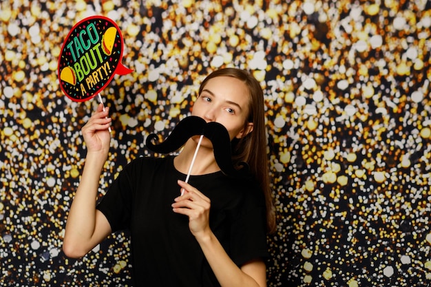 Cute lady holding boards and looking at the camera on gilded background