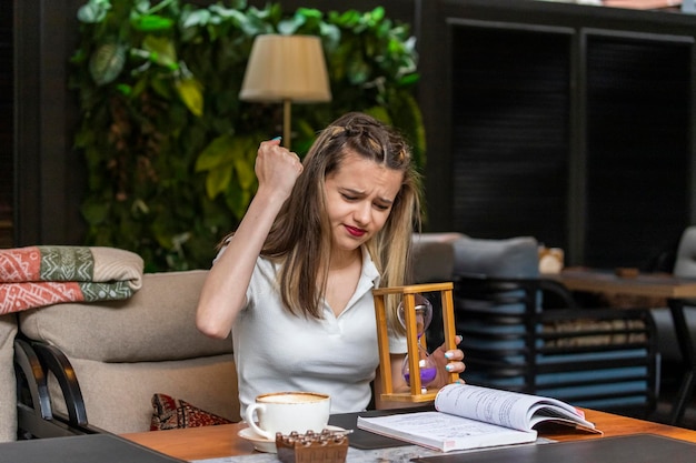 Free photo cute lady holding hourglass and squeezed her fist