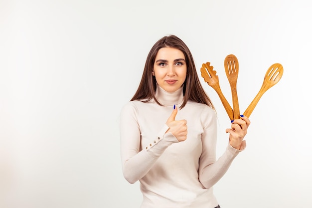 Free photo cute lady holding wooden spoons and gesture thumb up